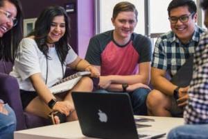 HSU students smiling 和  watching video on Mac laptop